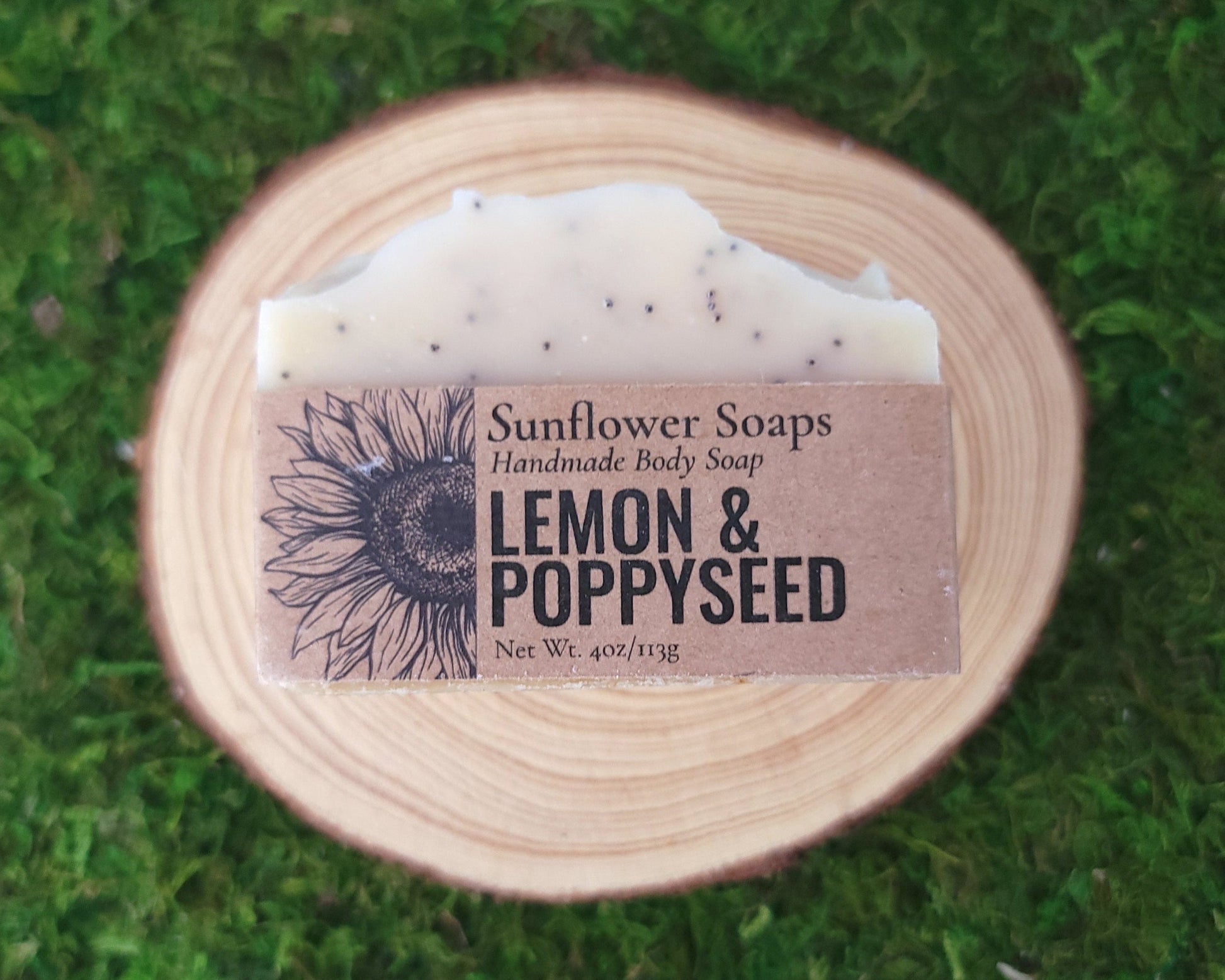 Handmade body soap bar with 'Sunflower Soaps' label on a green moss background